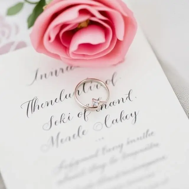 Wedding rings resting on a calligraphed invitation suite.